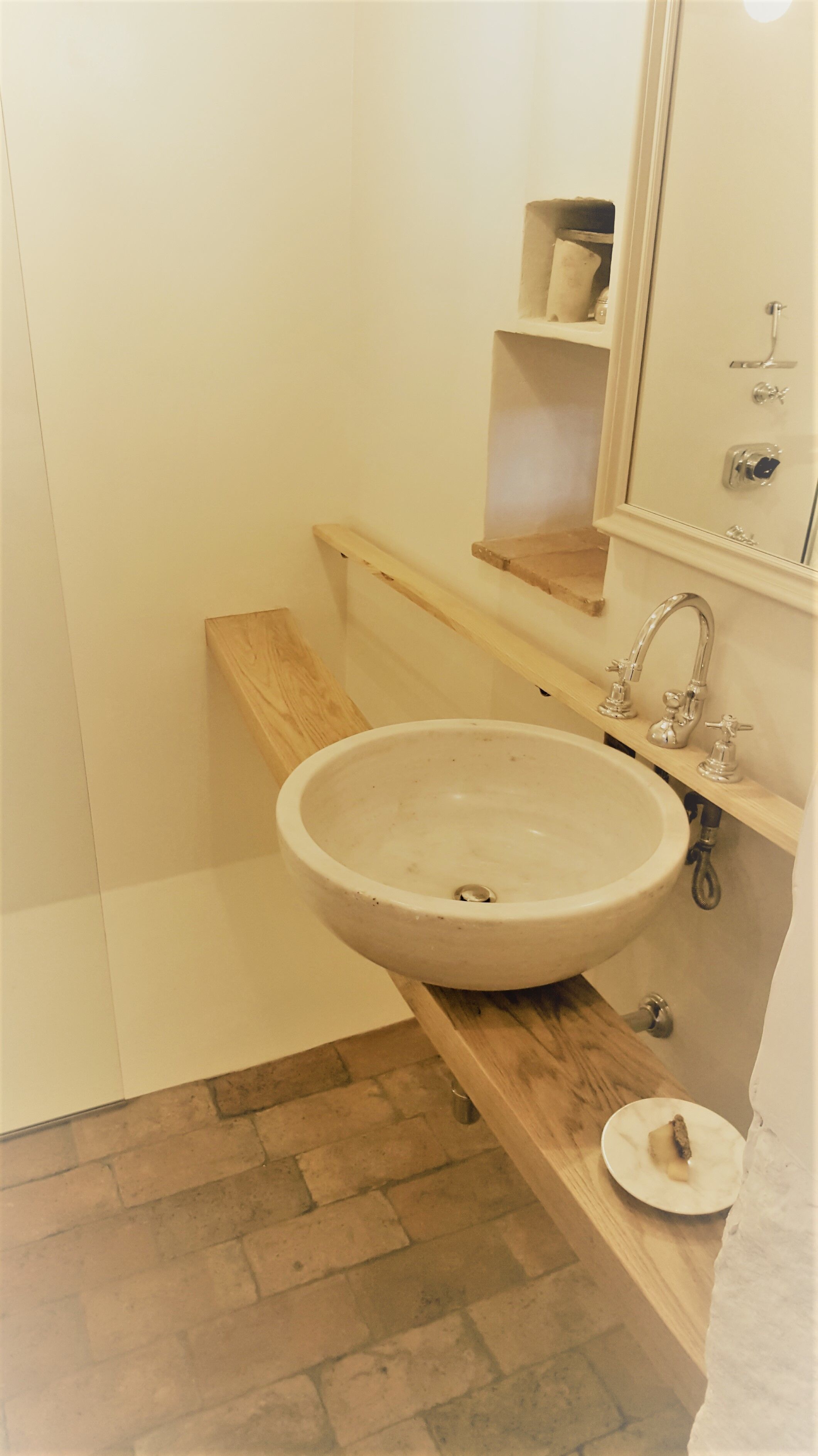 Un baño con lavamanos blanco, tocador de madera y espejo sobre el lavamanos.