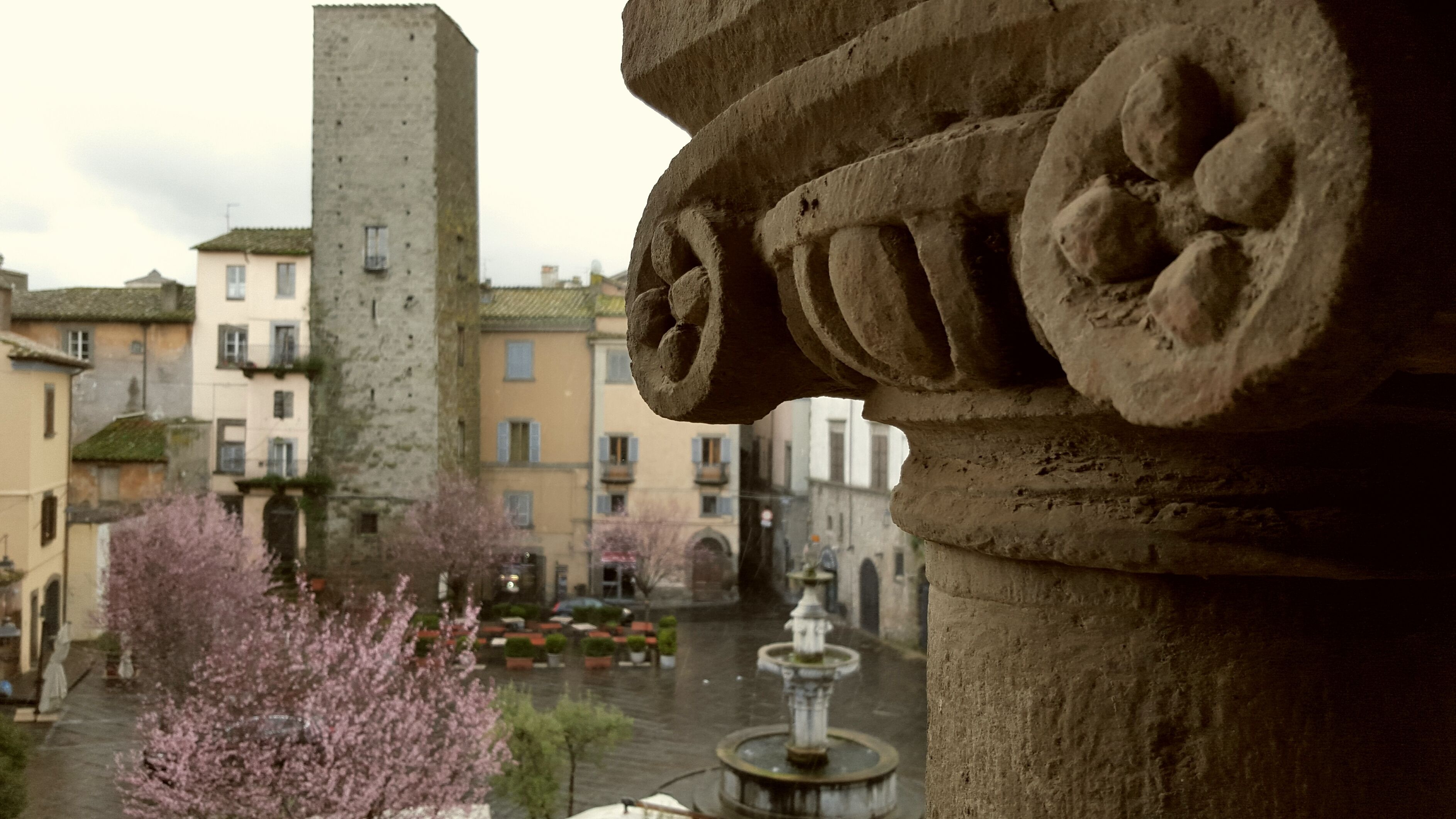 A stone architectural detail with a fountain in the background.