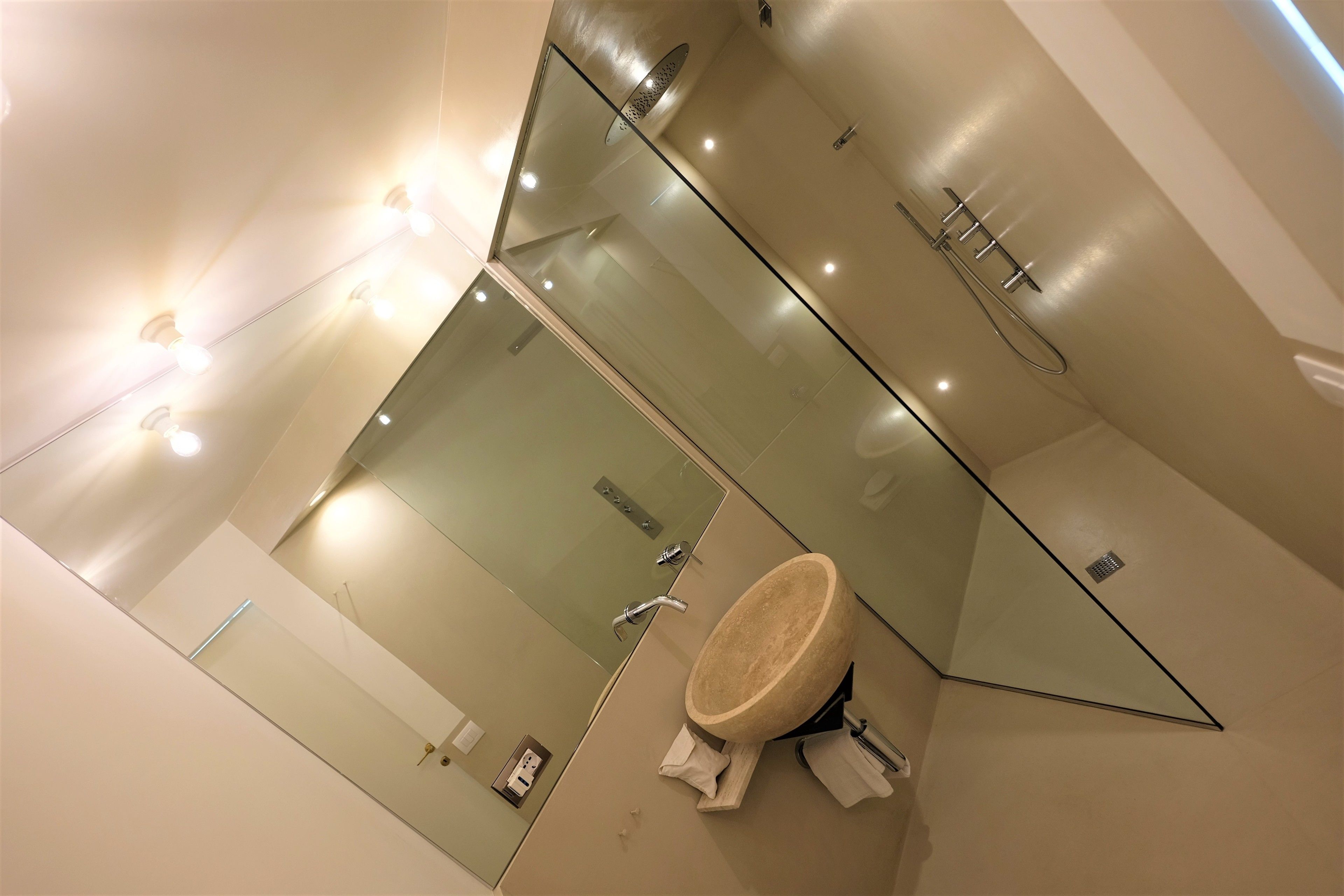 A modern bathroom with a large mirror, a round sink, and a shower area.