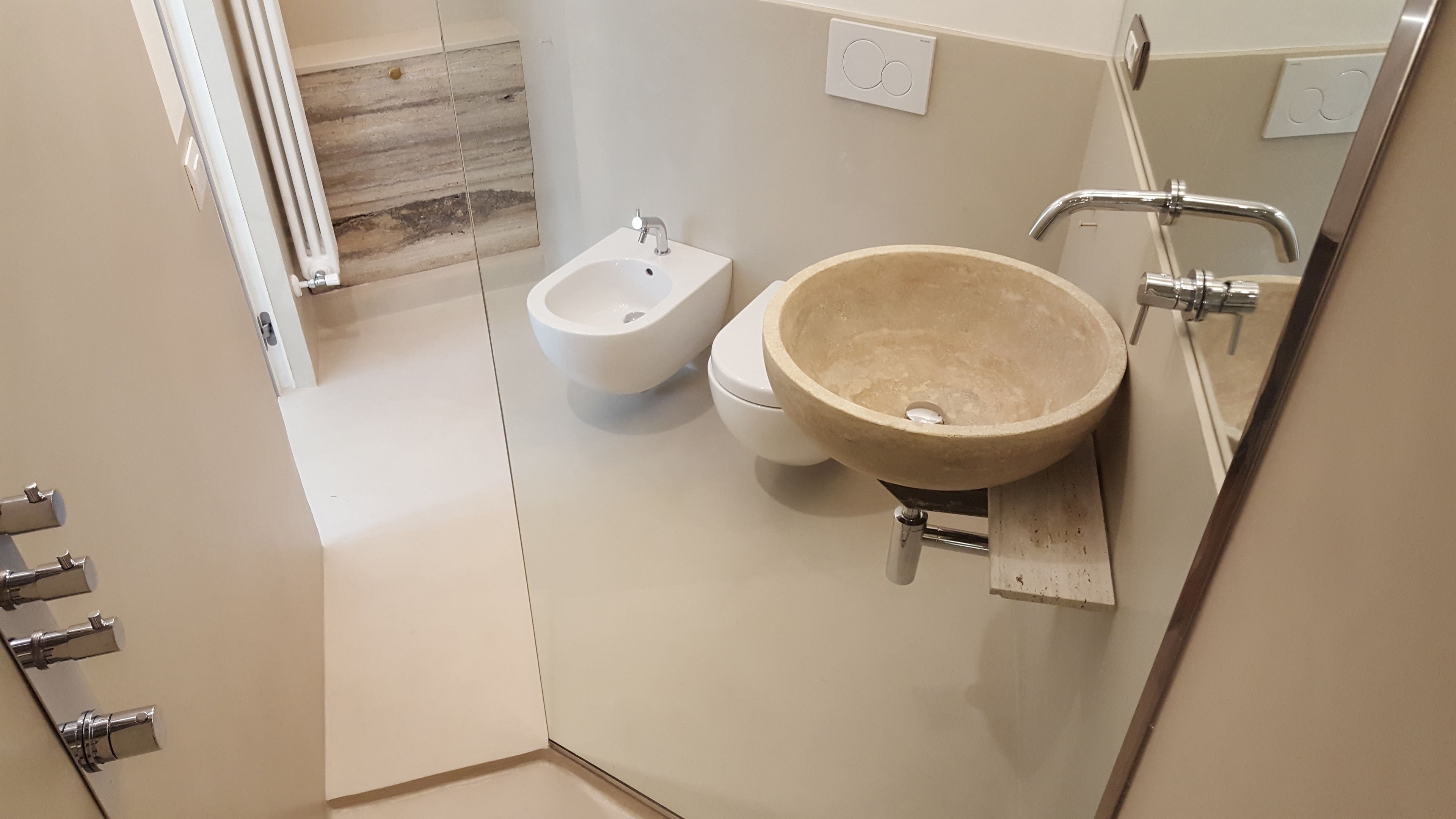 A modern bathroom with a large beige sink, a bidet, and a toilet.