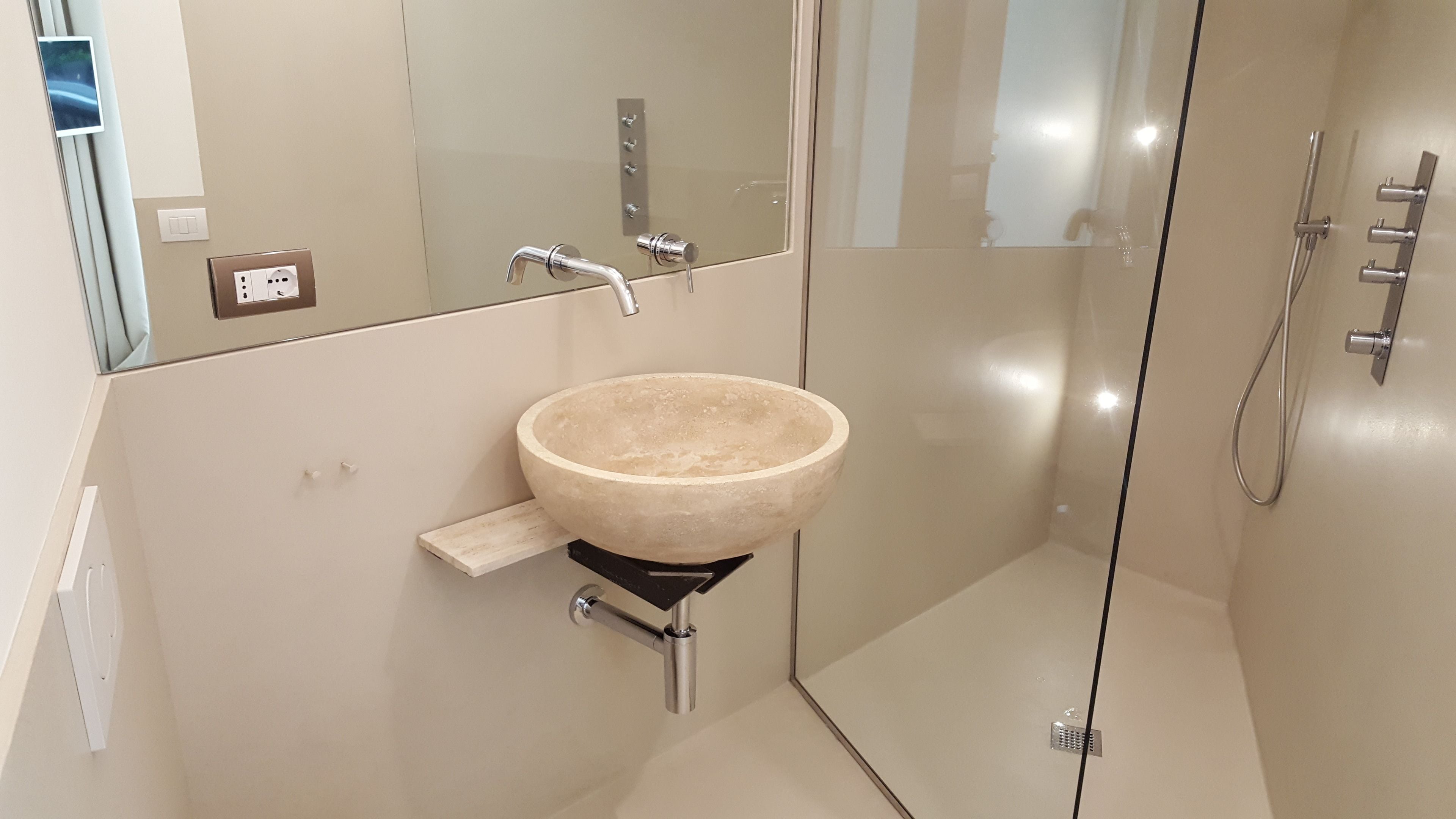 A modern bathroom with a large, round, beige sink mounted on a black pedestal.