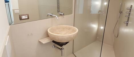 A modern bathroom with a large, round, beige sink mounted on a black pedestal.