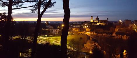 A view of a cityscape at dusk with a prominent building featuring a dome and clock tower.