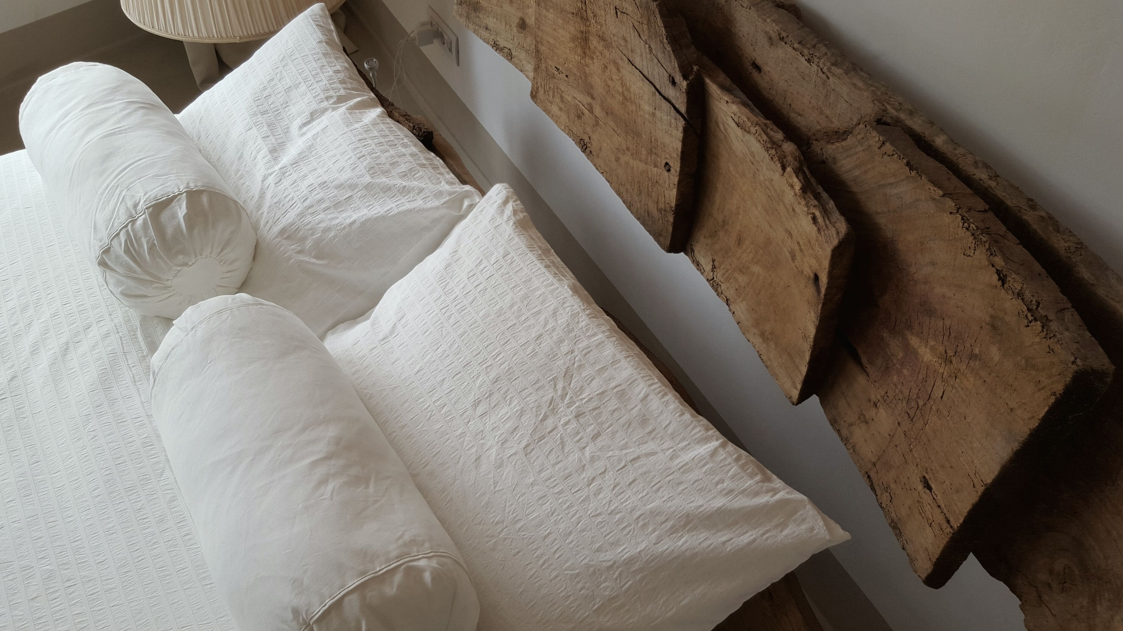 A bed with white pillows and a wooden headboard.
