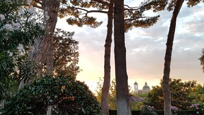 A garden with tall trees and a distant view of a building with a dome and bell tower. - B&B A Piazza del Gesù (Viterbo)