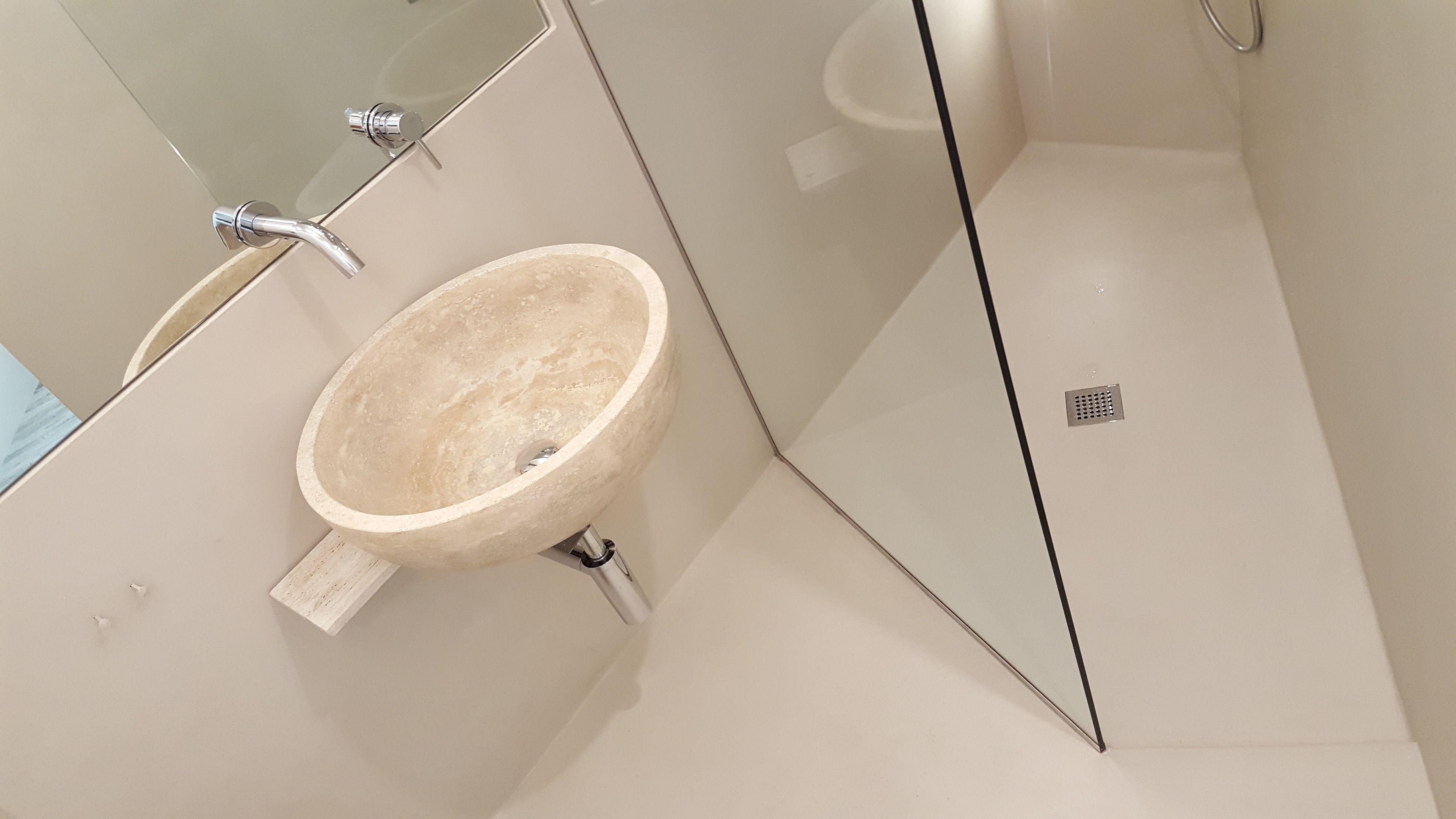 Un baño con un lavamanos color beige, un espejo y una zona de ducha.