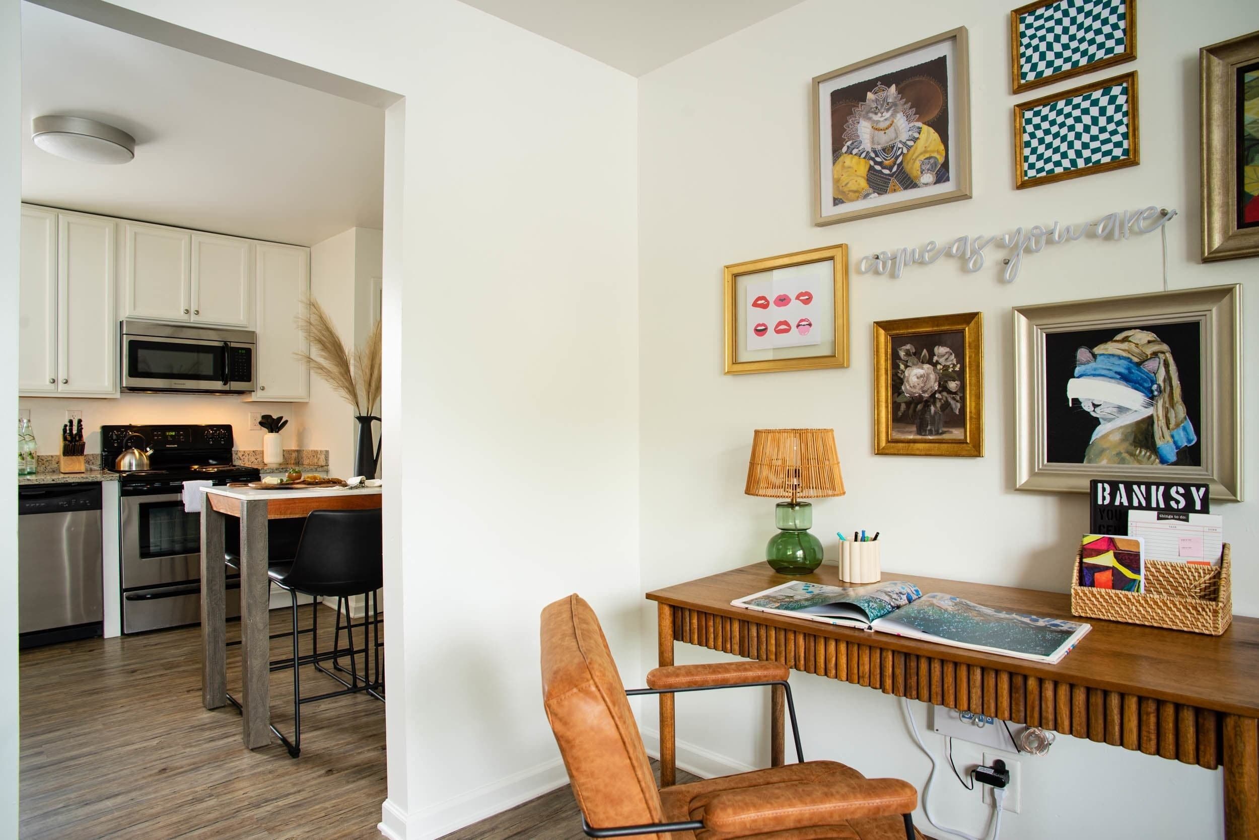 A modern kitchen with white cabinets, stainless steel appliances, and a wooden dining table with a chair.