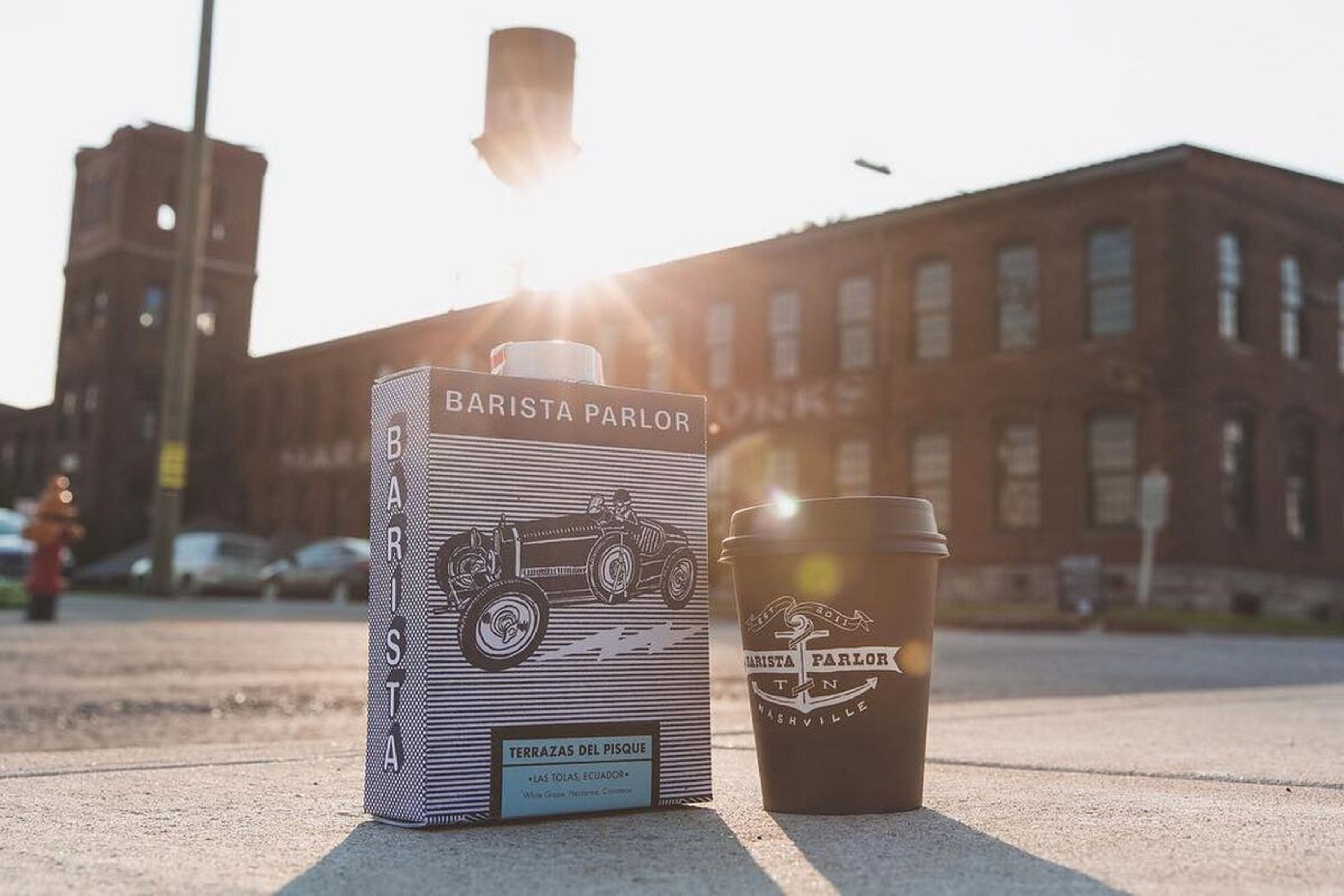 A coffee cup and a box with the text "Barista Parlor" and "TERRAZAS DEL PISQUE" on a sidewalk.