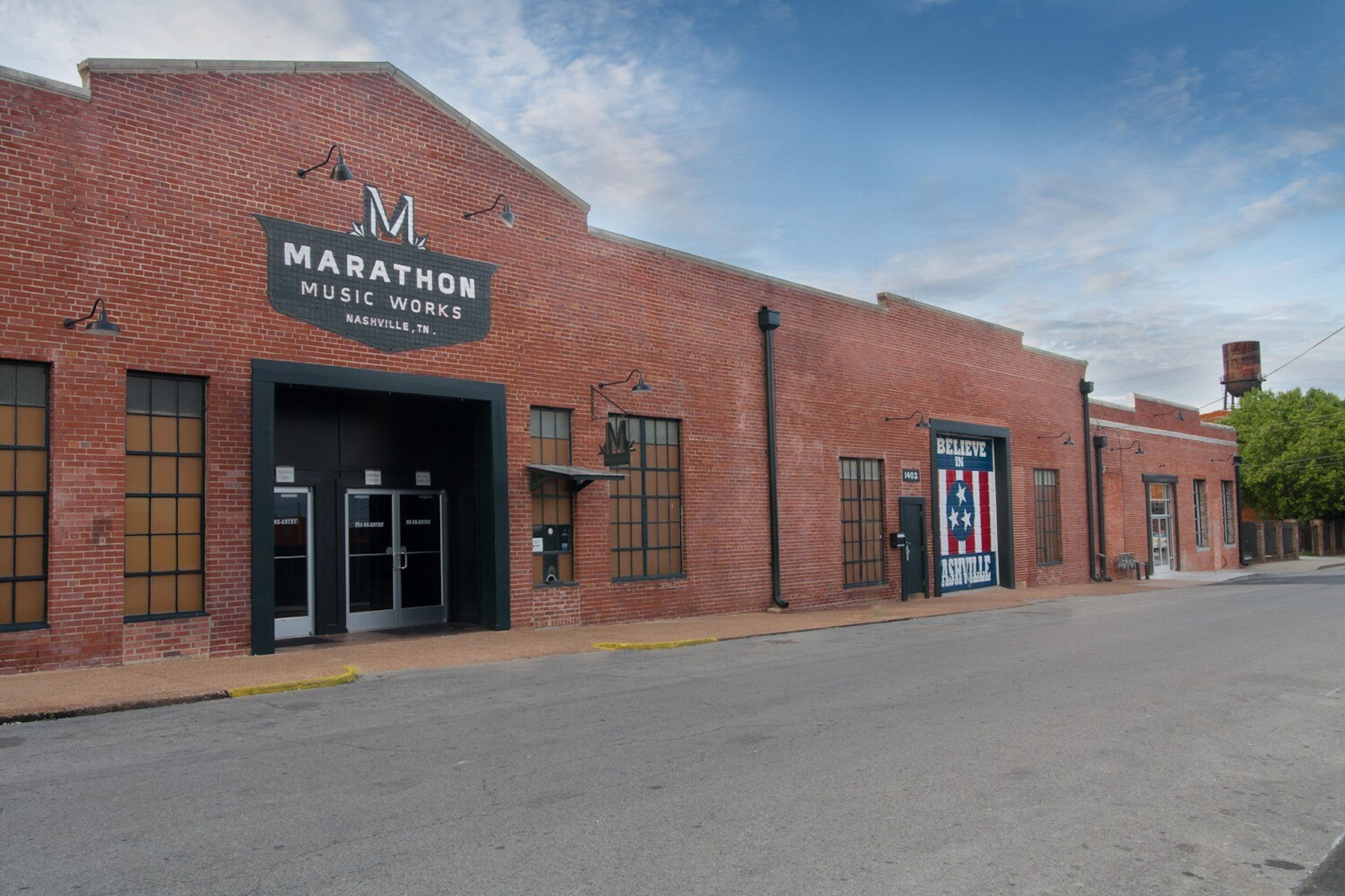 A brick building with a sign reading "Marathon Music Works" and a smaller sign for "Believe in Asheville."