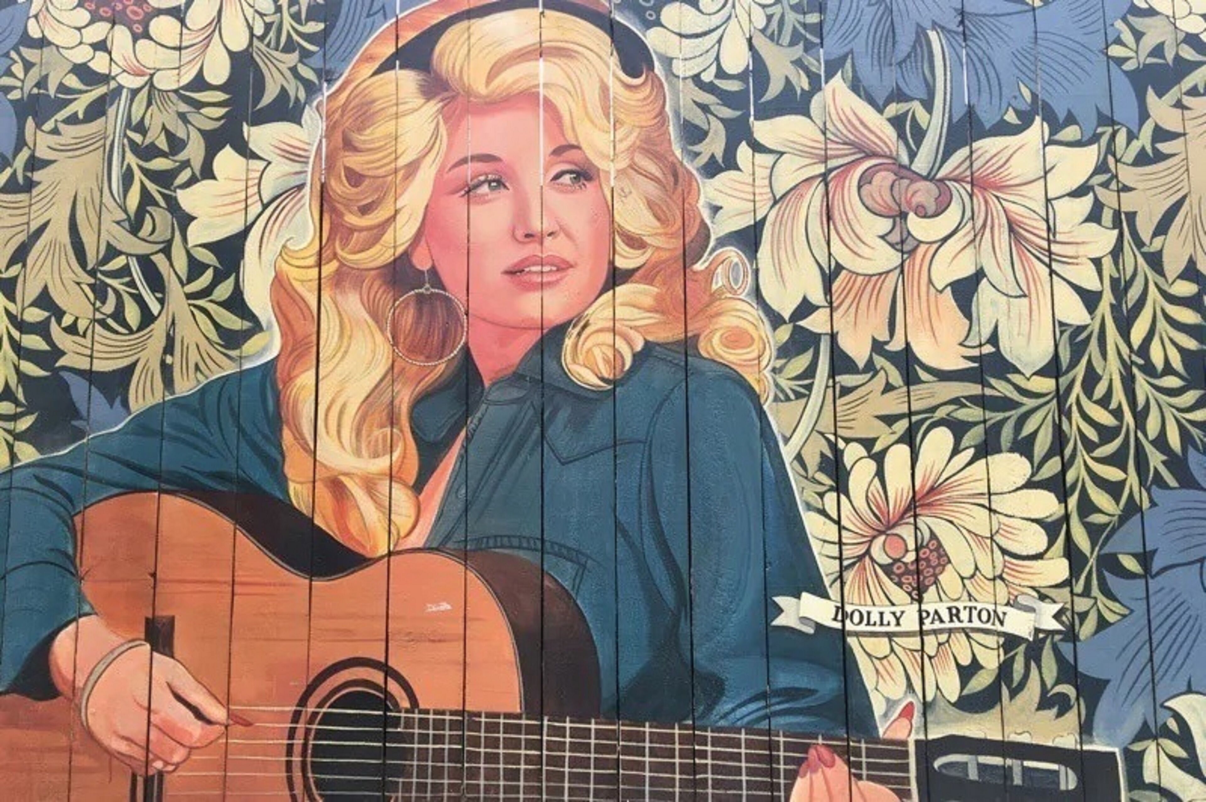 A mural of a person playing a guitar with floral patterns in the background.
