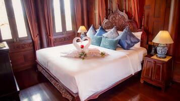 Habitación de hotel con una cama grande, un cabecero decorado y almohadones decorativos.