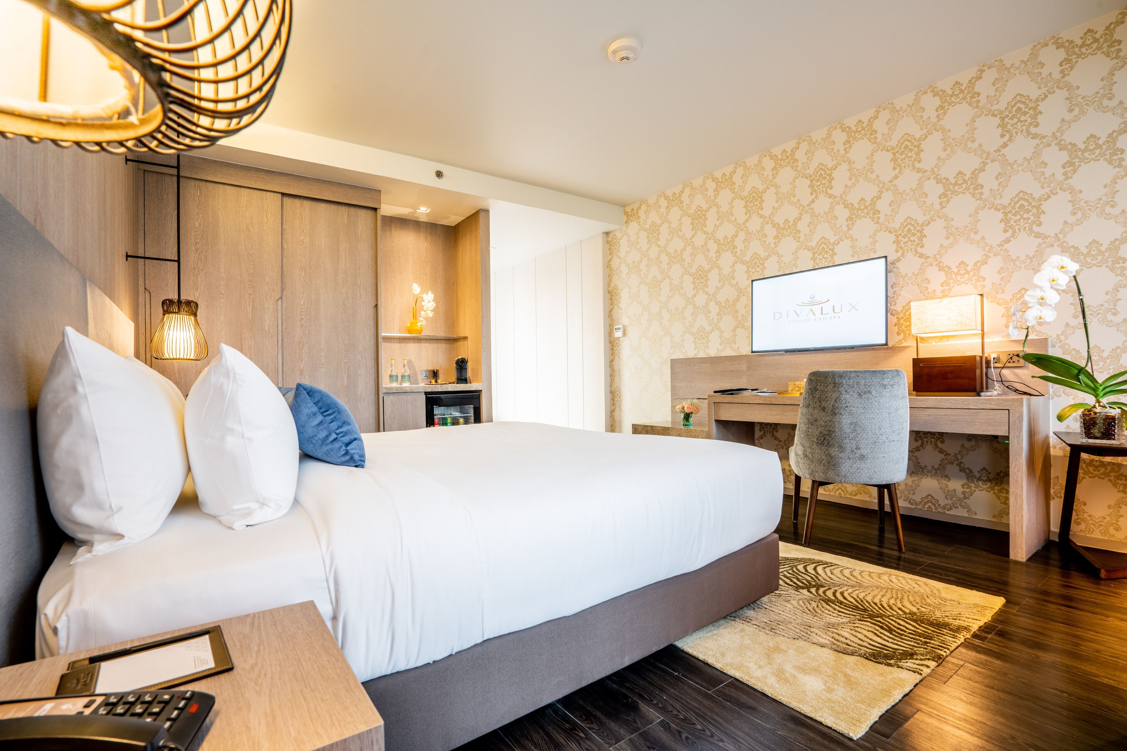A modern hotel room with a large bed, a desk, a television, and a small workspace.