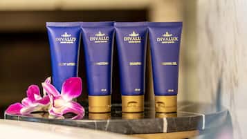 Four blue tubes of Divalux body care products on a marble surface with a purple orchid.