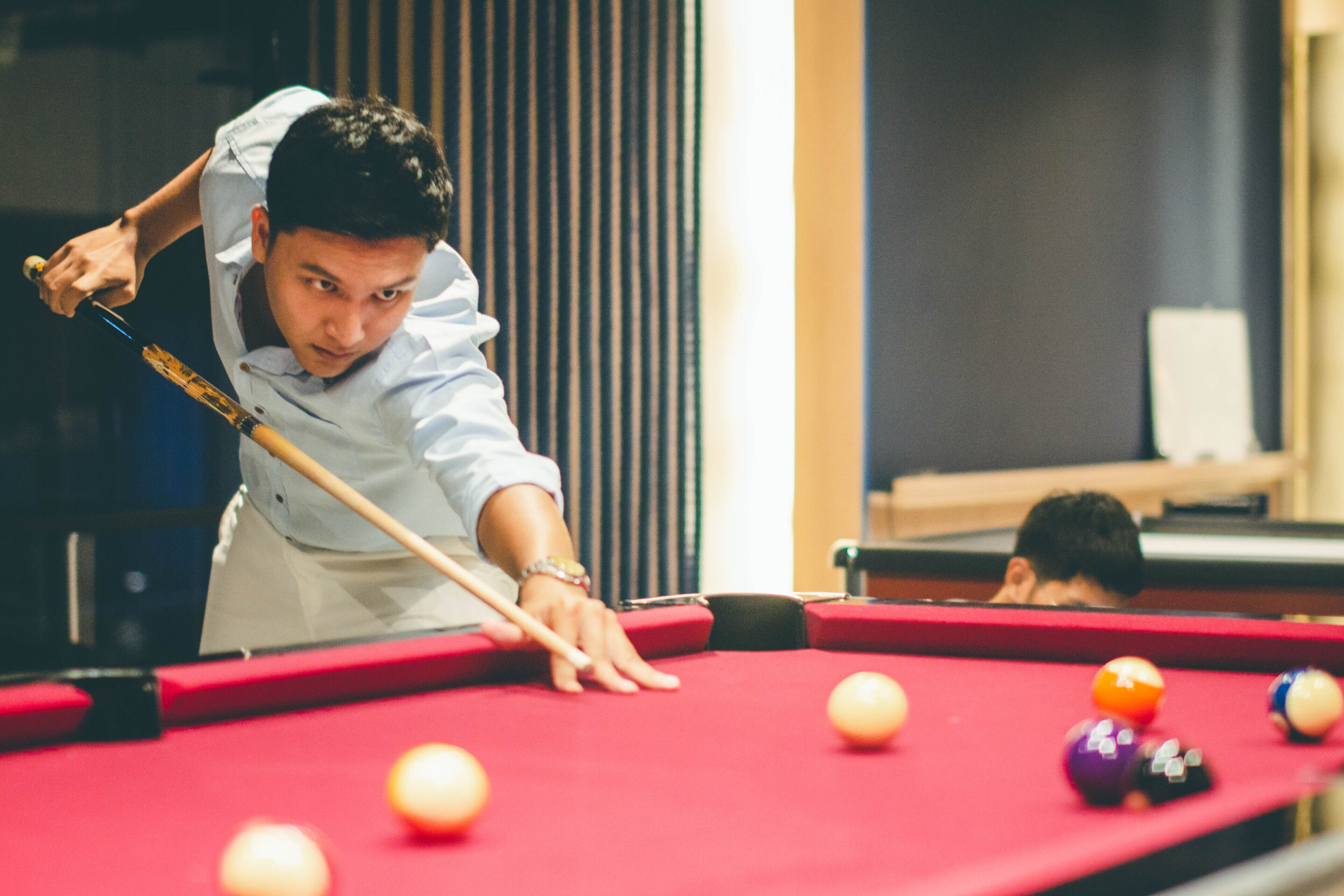 A pool table with balls and a person playing.