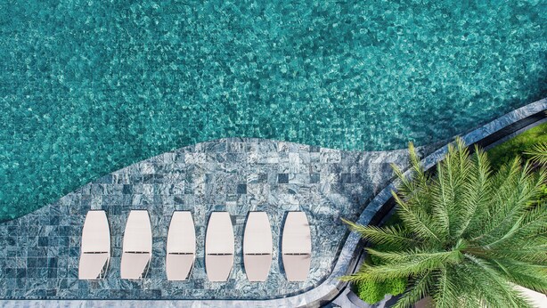 An aerial view of a swimming pool with clear water, surrounded by a tiled deck with lounge chairs. - Divalux Resort & Spa Bangkok, Suvarnabhumi Airport (Bang Sao Thong)