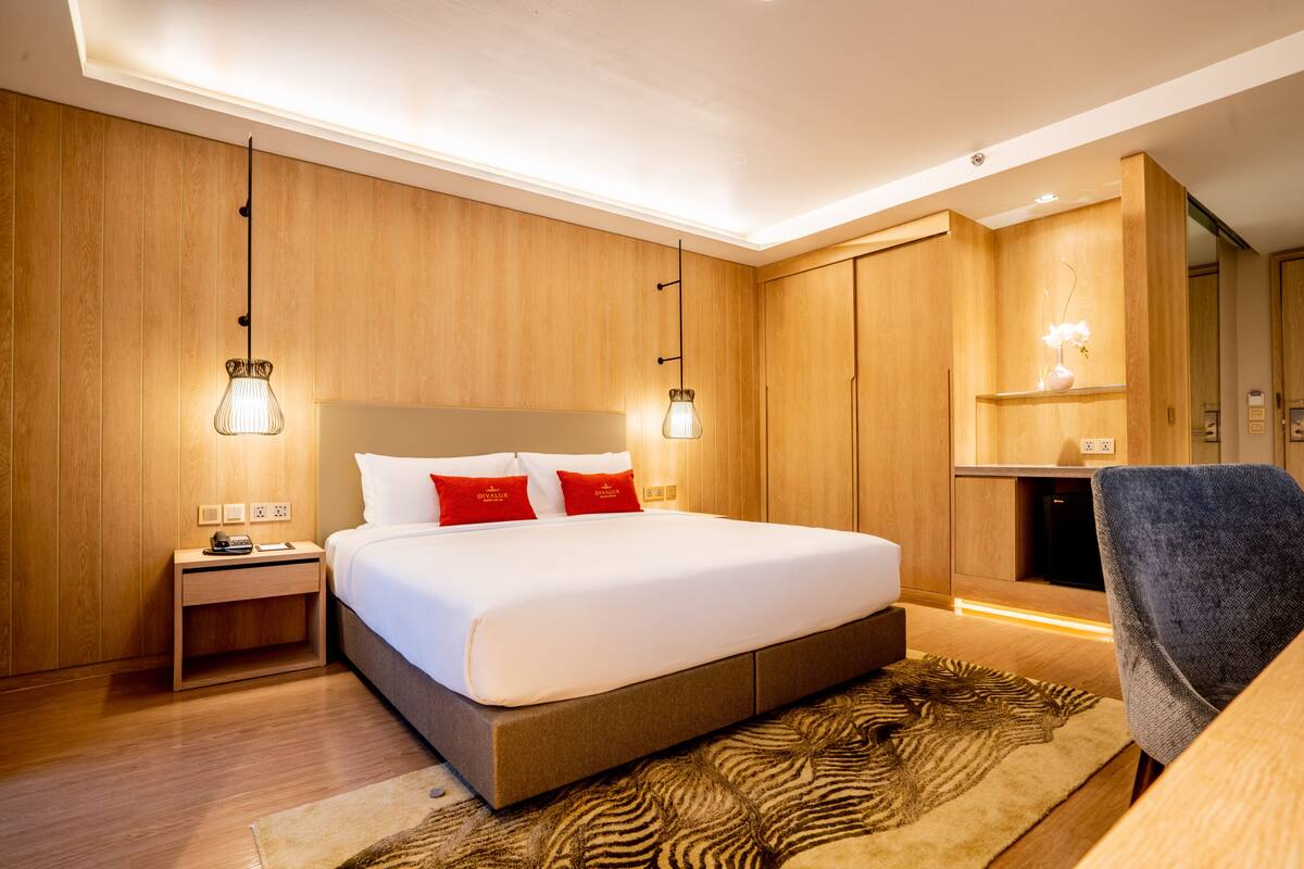 A modern hotel room with a large bed, wooden panel walls, and a zebra-patterned rug.