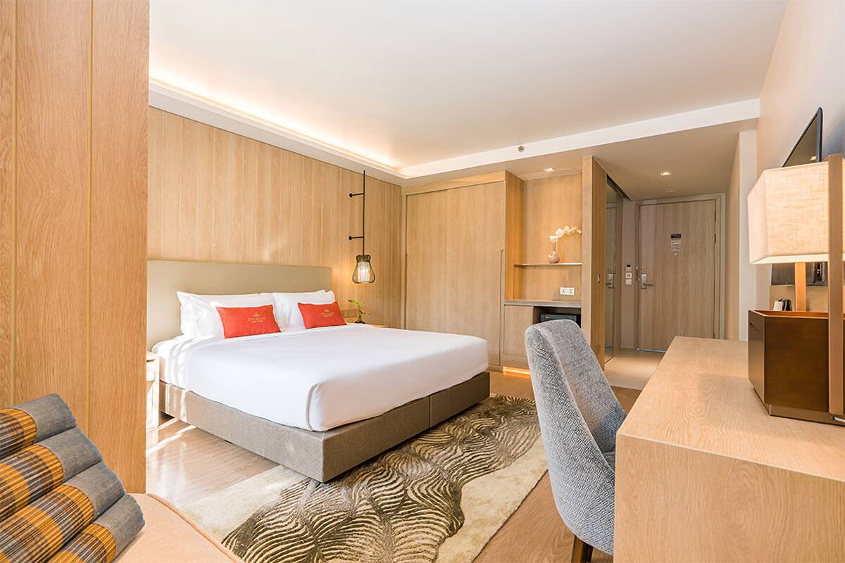 A modern hotel room with a large bed, a desk, and a chair.