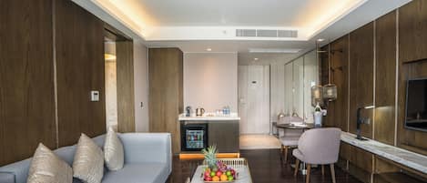 Una sala de estar moderna con un sofá, una mesa de centro y una zona de comedor con televisor y mostrador de cocina.