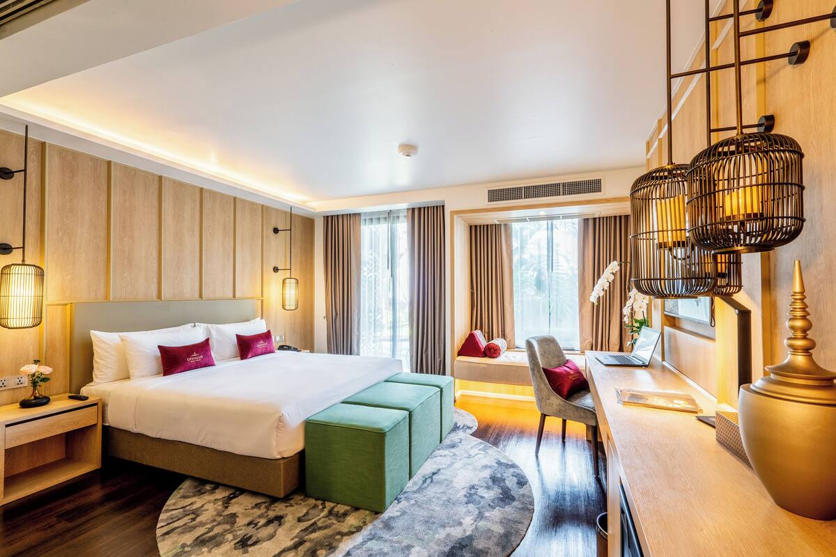A modern hotel room with a large bed, a desk, and a seating area.