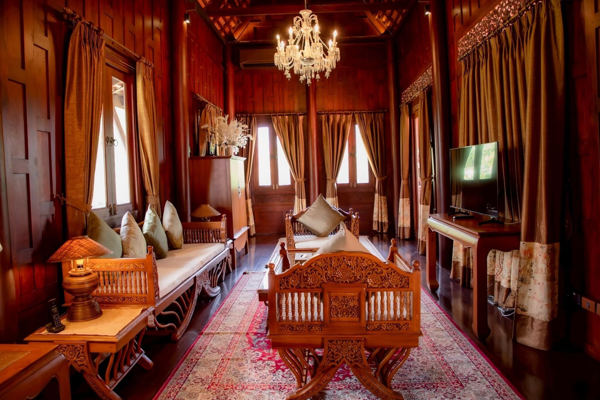 A traditional wooden room with a bed, a television, and a chandelier.