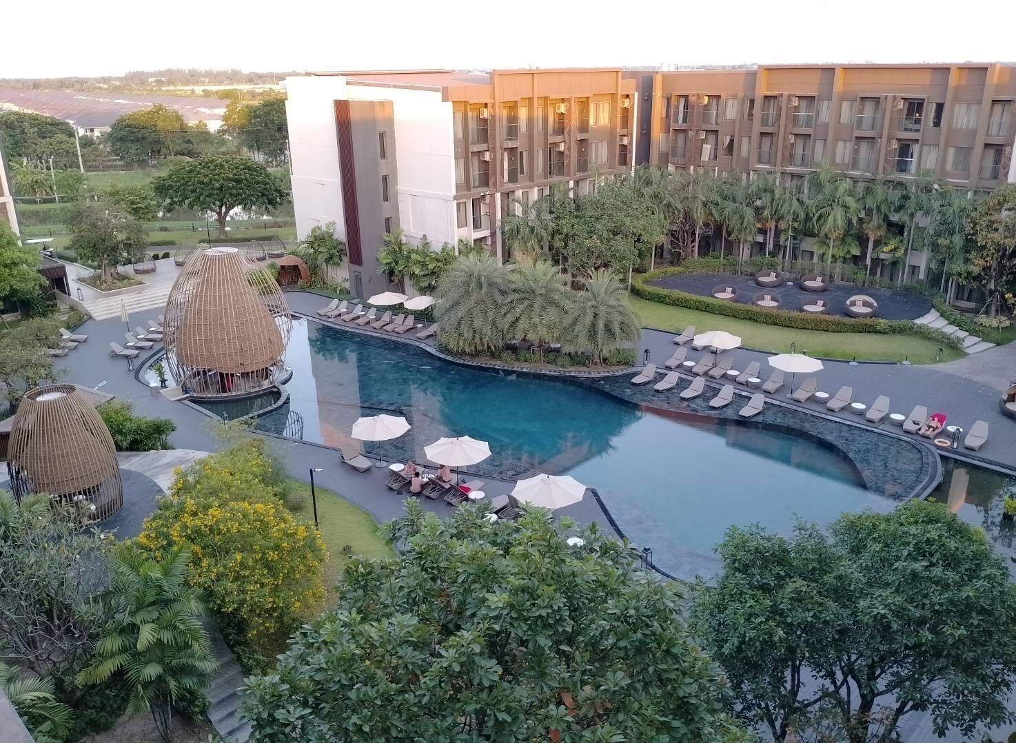 A resort with a large swimming pool, lounge areas, and a modern building with multiple floors.