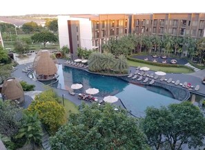 A resort with a large swimming pool, lounge areas, and a modern building with multiple floors.