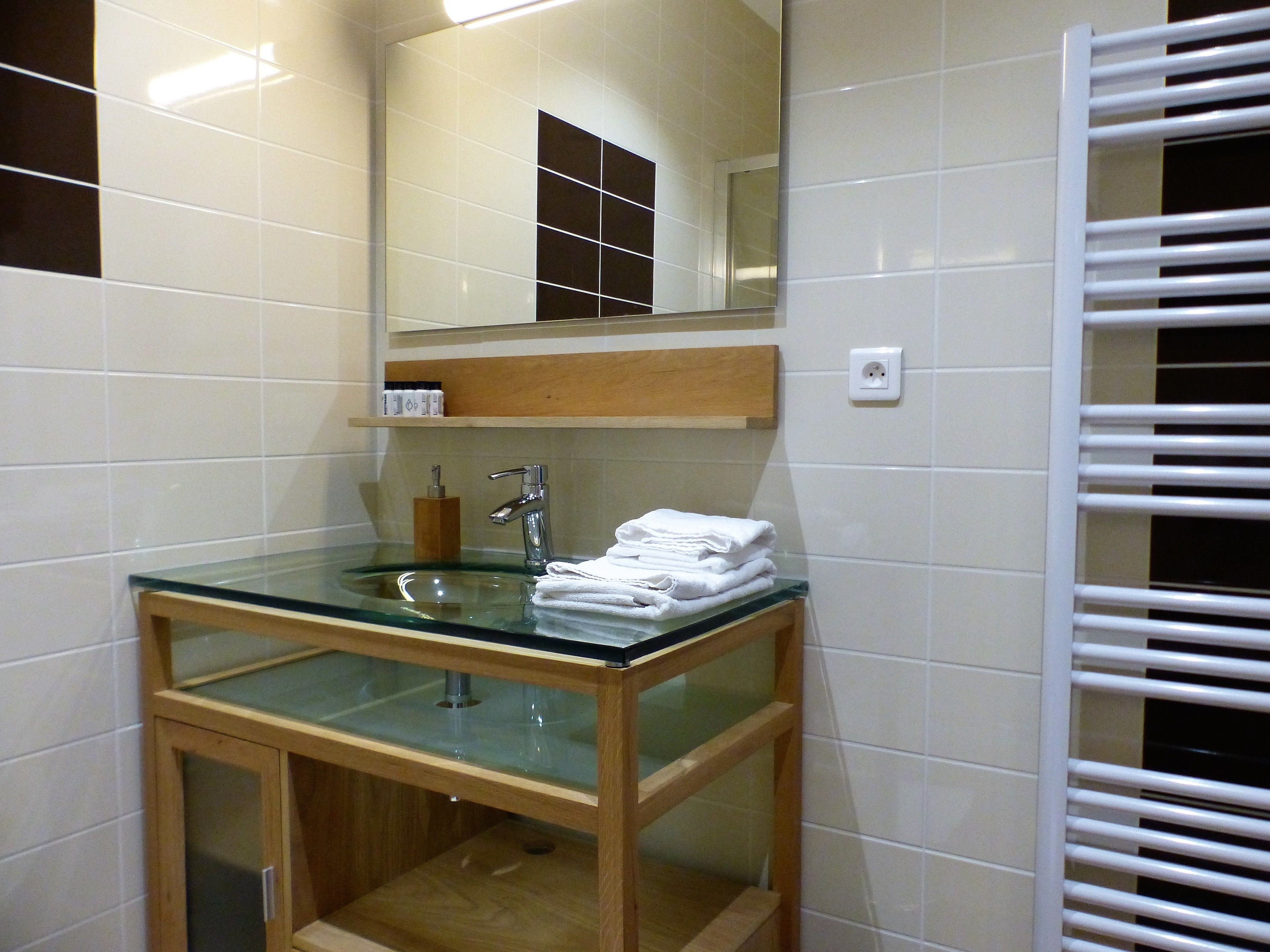 A bathroom with a glass sink, wooden cabinet, and a mirror above the sink.