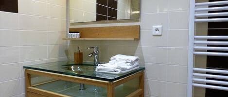 A bathroom with a glass sink, wooden cabinet, and a mirror above the sink.