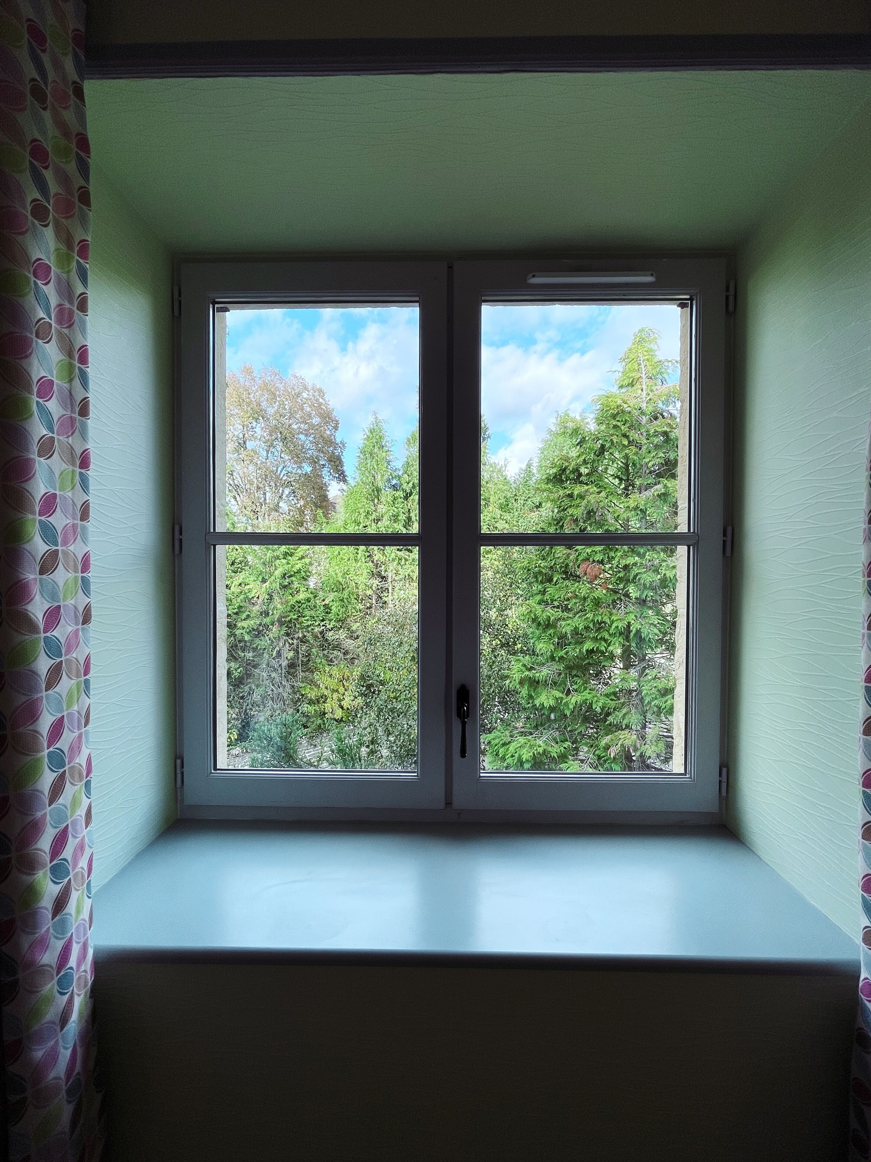 Une pièce avec une fenêtre donnant sur un jardin.
