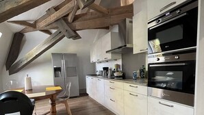 Eine moderne Küche mit Holzbalken, weißen Schränken und einem eingebauten Backofen.