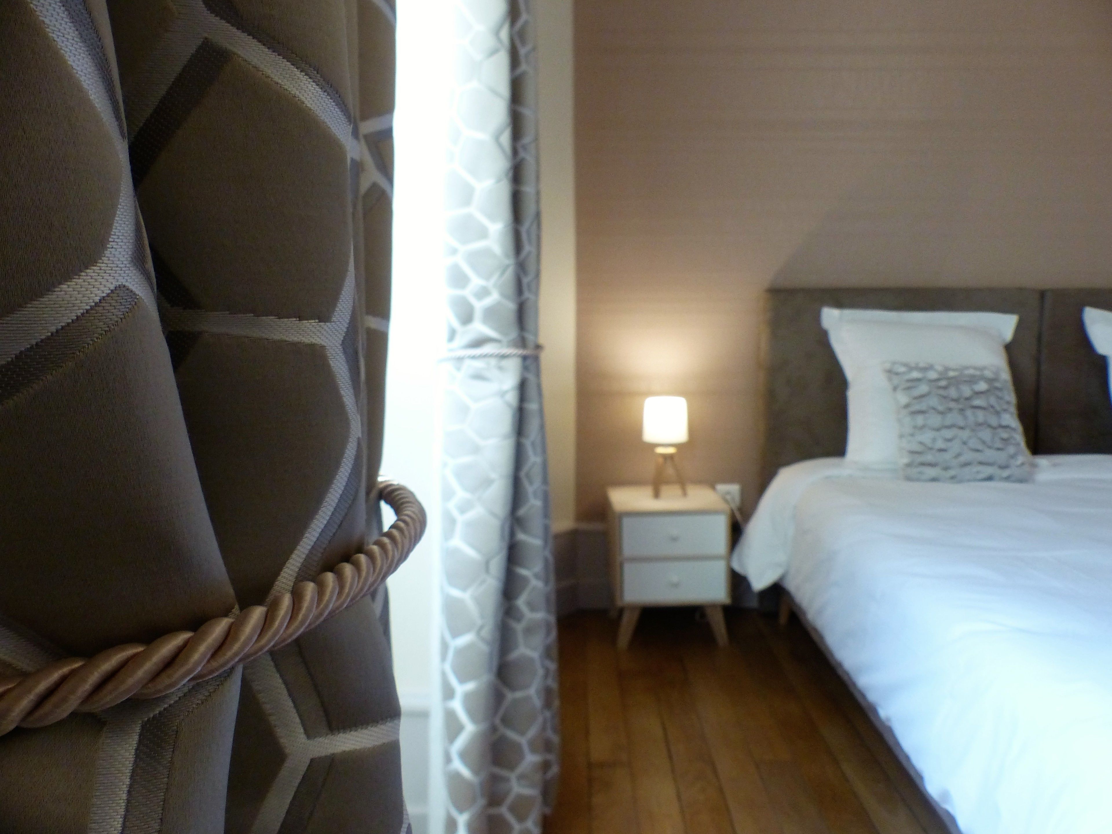 Ein Schlafzimmer mit Bett, Nachttisch, Lampe und einem Sessel.