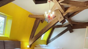 Ein Schlafzimmer mit zwei Betten, Holzbalken, einer Chandelierleuchtre und einem Fenster.