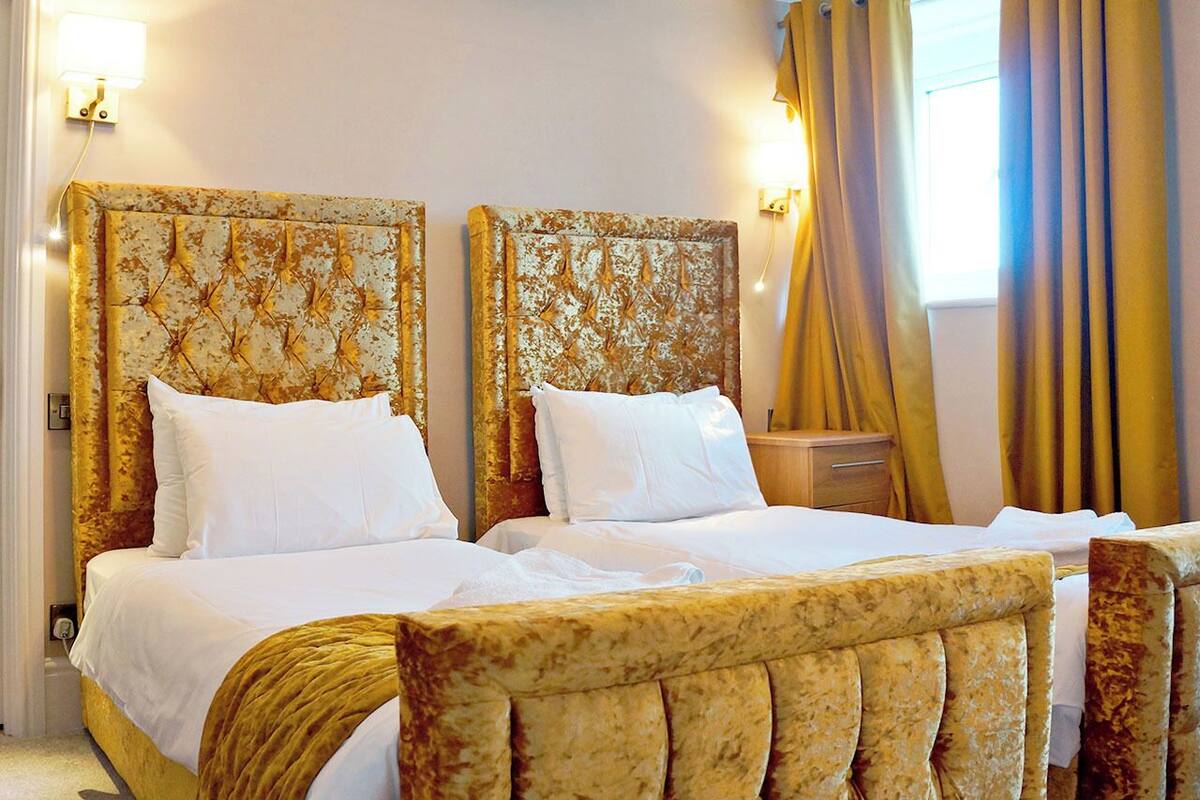A double bed with a headboard, a bedside table, and a window with curtains.