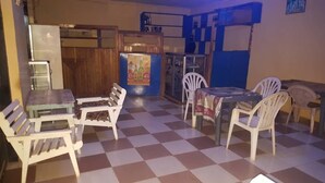 A room with a checkered floor, a table with chairs, a refrigerator, a wooden cabinet, and a poster on the wall. - Topway Hotel (Nkawkaw)