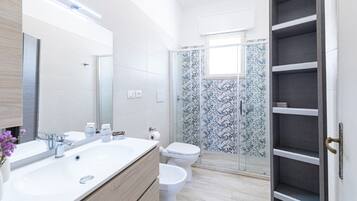 Ein modernes Badezimmer mit großem Waschbecken, Toilette und Duschbereich.