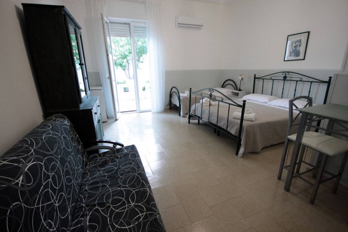 Una habitación con cama, escritorio, silla, sofá y armario.