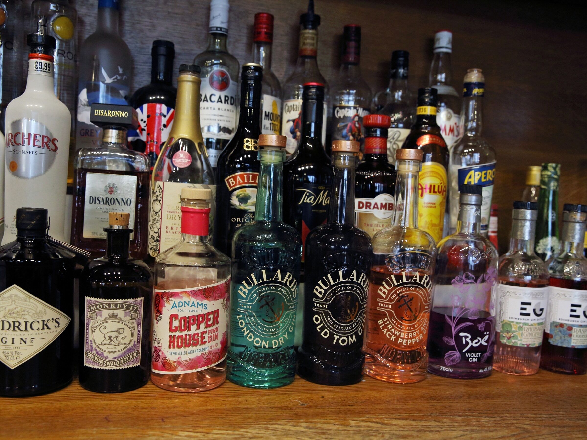 Diverse drankflessen op een plank.