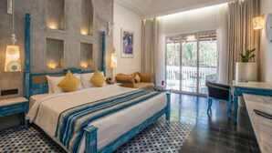 A spacious bedroom with a large bed, a seating area with a sofa and armchairs, a dining table, and a balcony with a view. - Maravilha a boutique stay (Assagao)