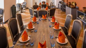 A dining area with a long table set for a meal, surrounded by chairs, with a chandelier above. - Maravilha a boutique stay (Assagao)