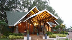 Un edificio moderno con tejado inclinado, mostrador de recepción y jardín bien cuidado.