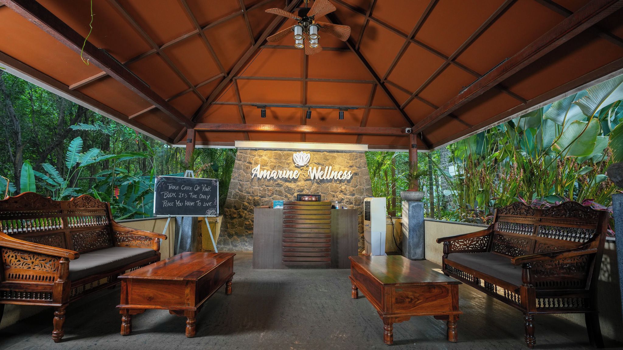A reception area with a stone wall, wooden furniture, and a sign reading 'Amarine Wellness'.