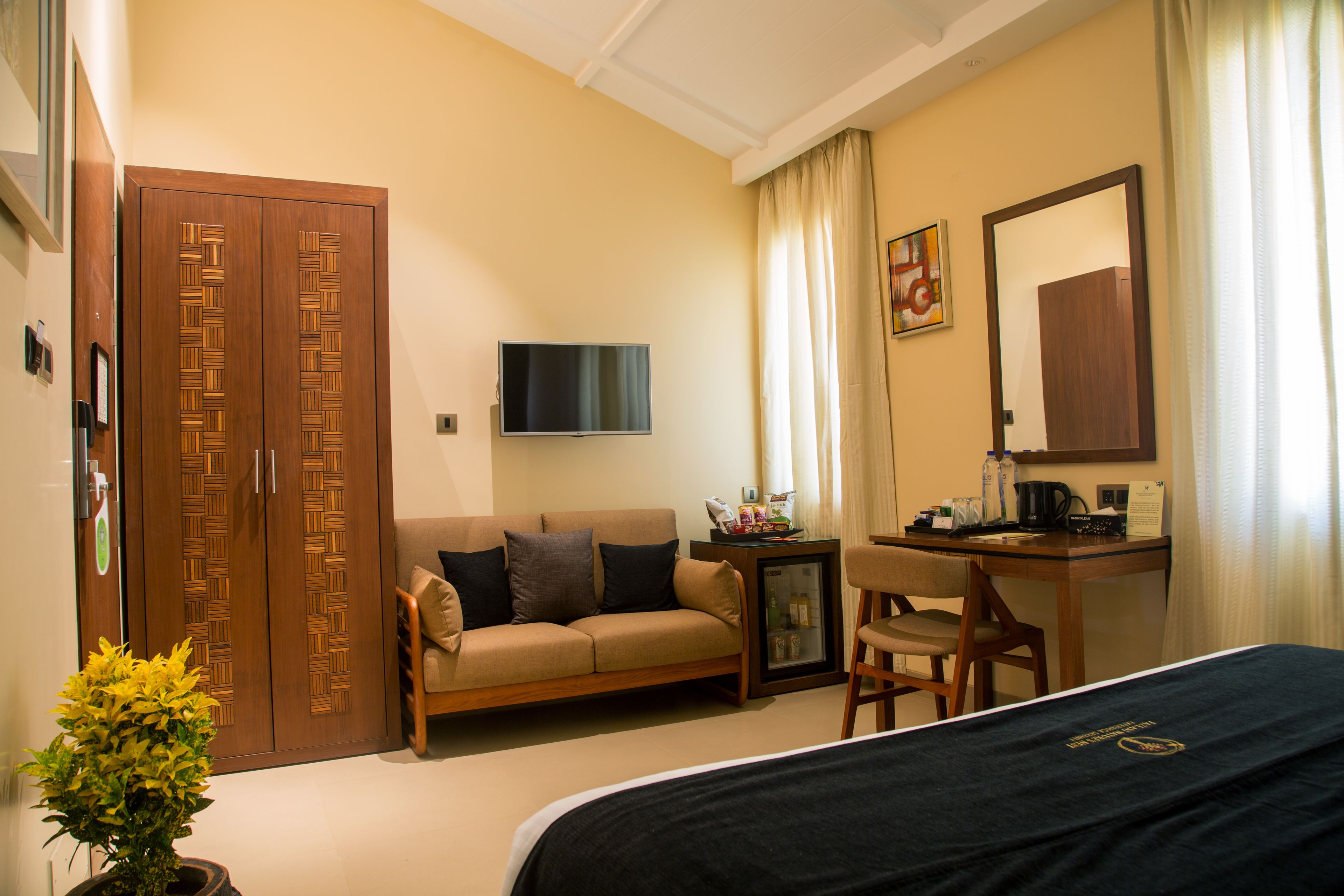 A hotel room with a bed, a sofa, a desk, a television, and a wardrobe.