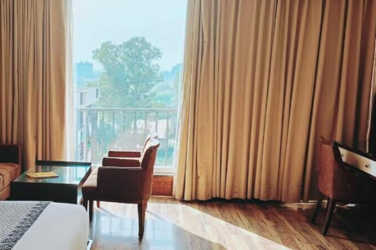 Une chambre d’hôtel comprenant un lit, un canapé, une chaise, une petite table et donnant sur l’extérieur.