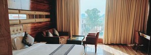 A hotel room with a bed, a sofa, a chair, a small table, and a view of the outdoors. - Hotel Vintage (Dera Bassi)
