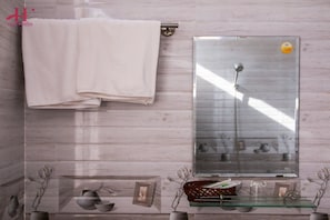Un baño con toallero, cabina de ducha de vidrio y repisa con objetos decorativos.