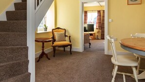 Una escalera conduce a una sala de estar con una mesa de comedor, sillas y un televisor al fondo.