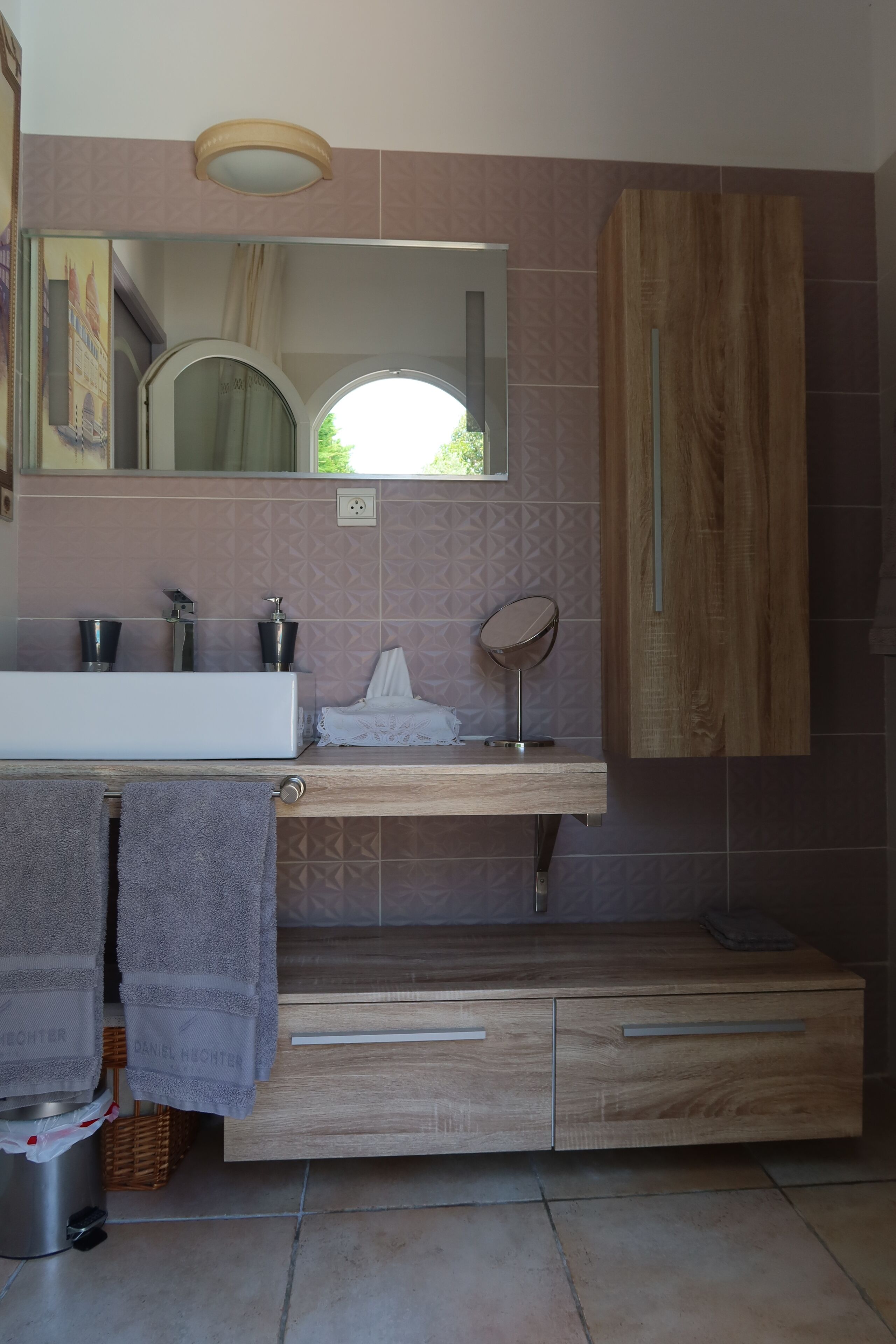 A modern bathroom with a wooden vanity, a large mirror, and a white sink.