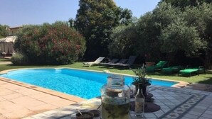 A swimming pool with lounge chairs and a tiled patio area.