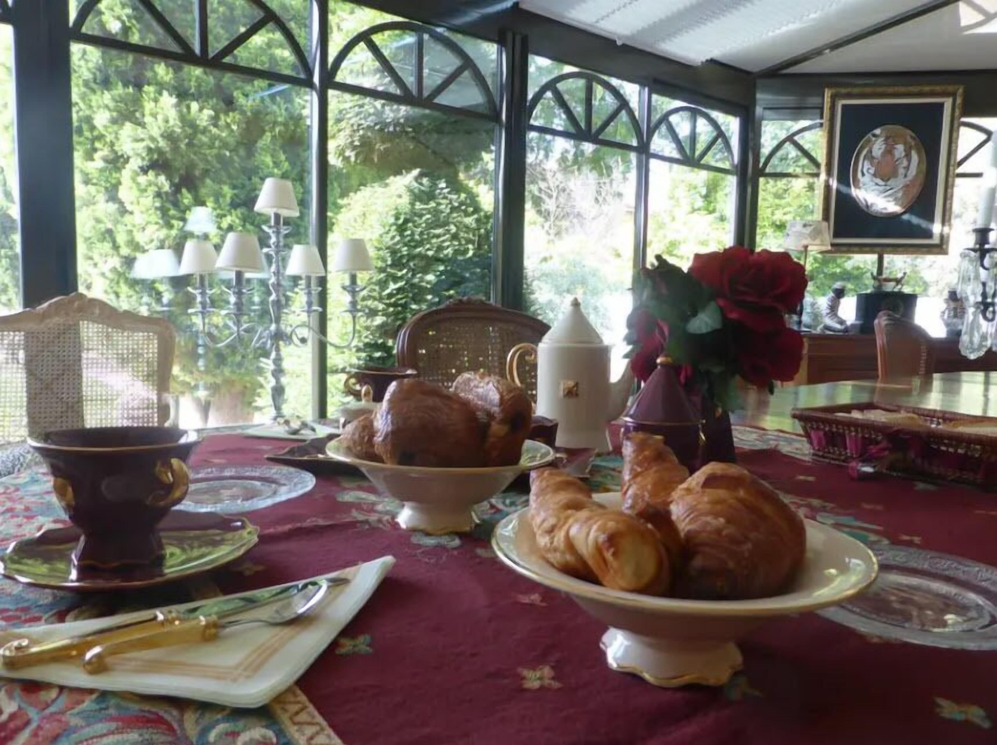 Een ontbijtruimte met een gedekte tafel, met croissants en een theepot.