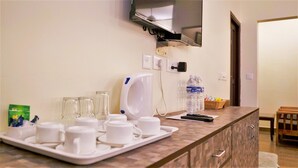 Ein Hotelzimmer mit Küchenzeile, einer Mikrowelle, einer Kaffeemaschine und einer Ablage mit Tassen und Gläsern.